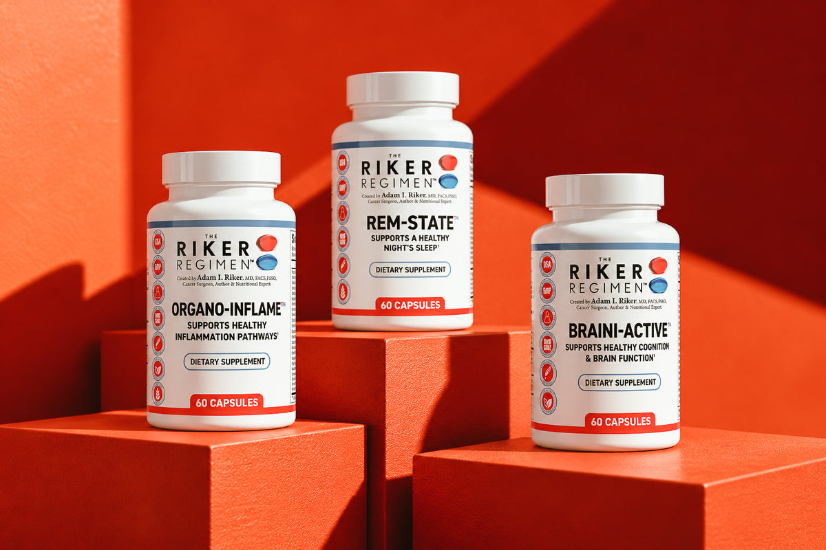 Three white supplement bottles from Riker Regimen stand on orange geometric blocks against a vivid orange background. The bottles are labeled Organo-Inflame, Rem-State, and Brain-Active, each with 60 capsules.
